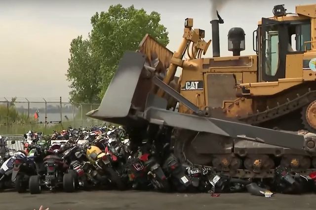 A bulldozer destroys a pile of dirt bikes at  Brooklyn auto pound.